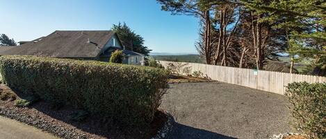 A residential driveway with a gravel path, a wooden fence, and a hedge.