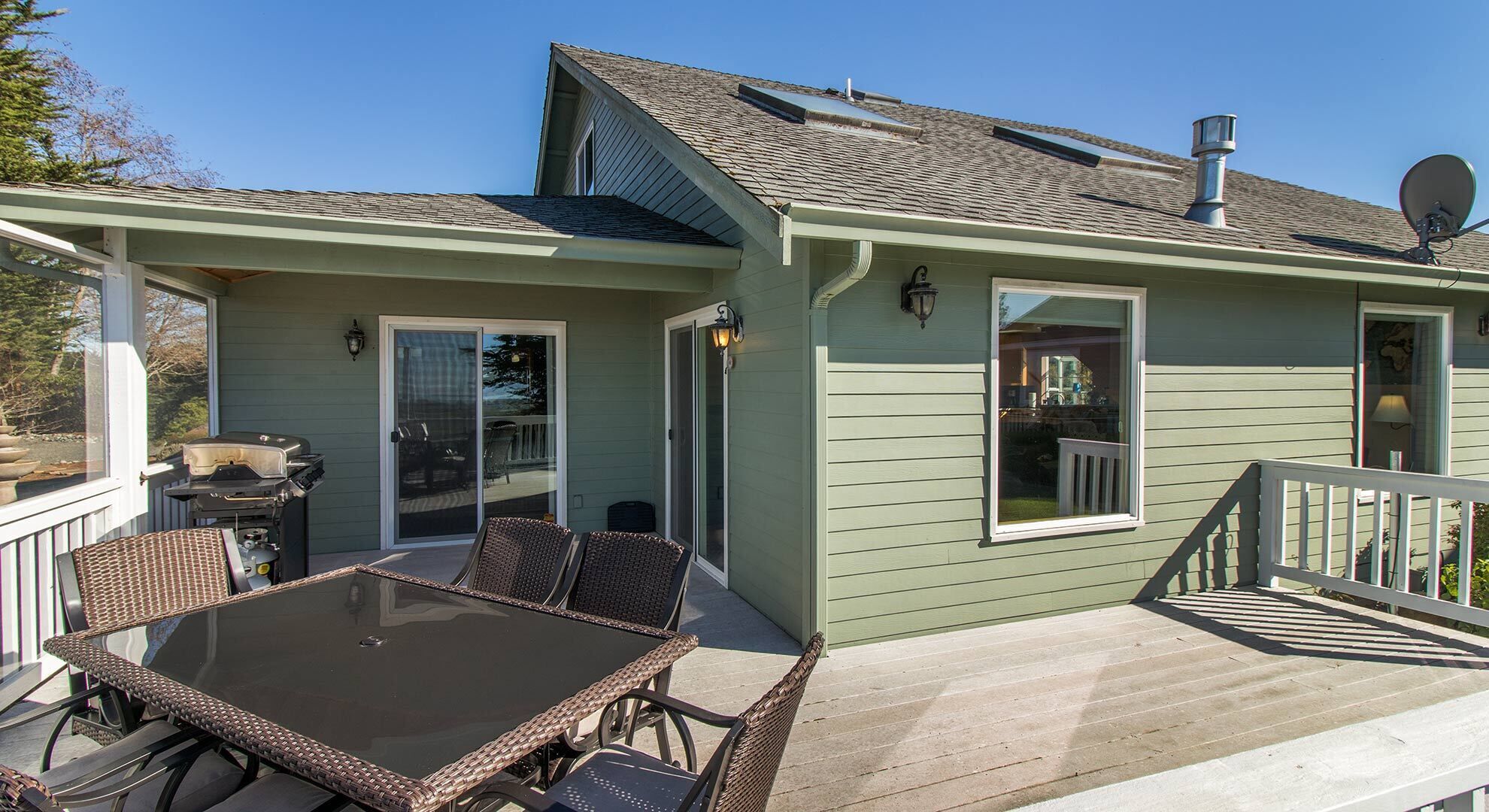 A covered patio with a table and chairs, a sliding glass door, and a small deck area.