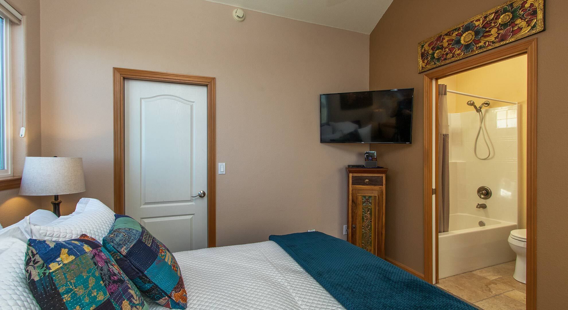 Une chambre d’hôtel avec un lit, une télévision, une salle de bain avec douche et une porte.