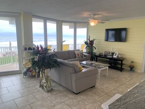 Relax in this ocean-view living room with a sofa, coffee table, and TV, surrounded by decorative plants and a statue.