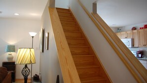 A staircase with wooden steps and a handrail, leading to a kitchen area with wooden cabinets and a white refrigerator. - Couples Mountain Retreat (Montebello)