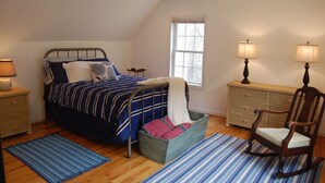 A bedroom with a bed, a rocking chair, a dresser, and a window. - Couples Mountain Retreat (Montebello)