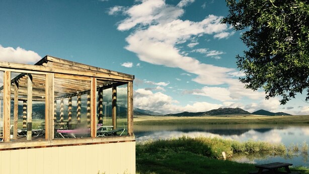 A wooden pavilion with a glass enclosure, a picnic table, and a view of a lake and mountains. - Private Lodge-Mtn Lake, Pool,Hot Tub, Affordable Family Reunion Sleeps 20+ (Westcliffe)