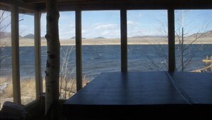 A room with a large window overlooking a body of water and distant mountains. - Private Lodge-Mtn Lake, Pool,Hot Tub, Affordable Family Reunion Sleeps 20+ (Westcliffe)