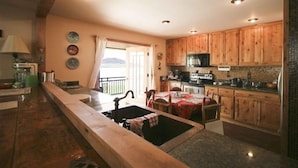 A kitchen with wooden cabinets, a built-in microwave, and a large window overlooking a scenic view. - Private Lodge-Mtn Lake, Pool,Hot Tub, Affordable Family Reunion Sleeps 20+ (Westcliffe)