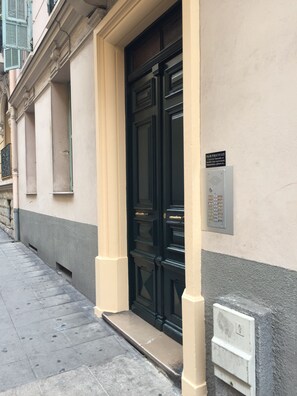 A building entrance with a black door, a mailbox, and a sign on the wall. - Family-friendly apartment in an authentic neighborhood and its open market (Nice)
