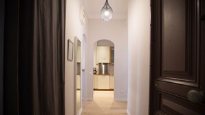 A hallway leading to a kitchen with wooden flooring and a hanging light fixture. - Family-friendly apartment in an authentic neighborhood and its open market (Nice)