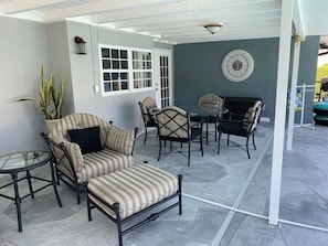 A covered patio area with a sofa, chairs, and a table.