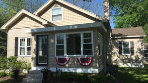A two-story house with a gabled roof, multiple windows, and a front porch. - 
VENETIAN'27SEND INQUIRY! Walk to Everything/Fenced Yard/Enclosed Front Porch/AC (Charlevoix)
