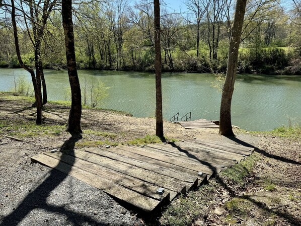 A wooden dock leading into a calm lake surrounded by trees.