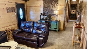 Een knus interieur van een blokhut met een leren bank, een houten kast en een decoratief wandobject.