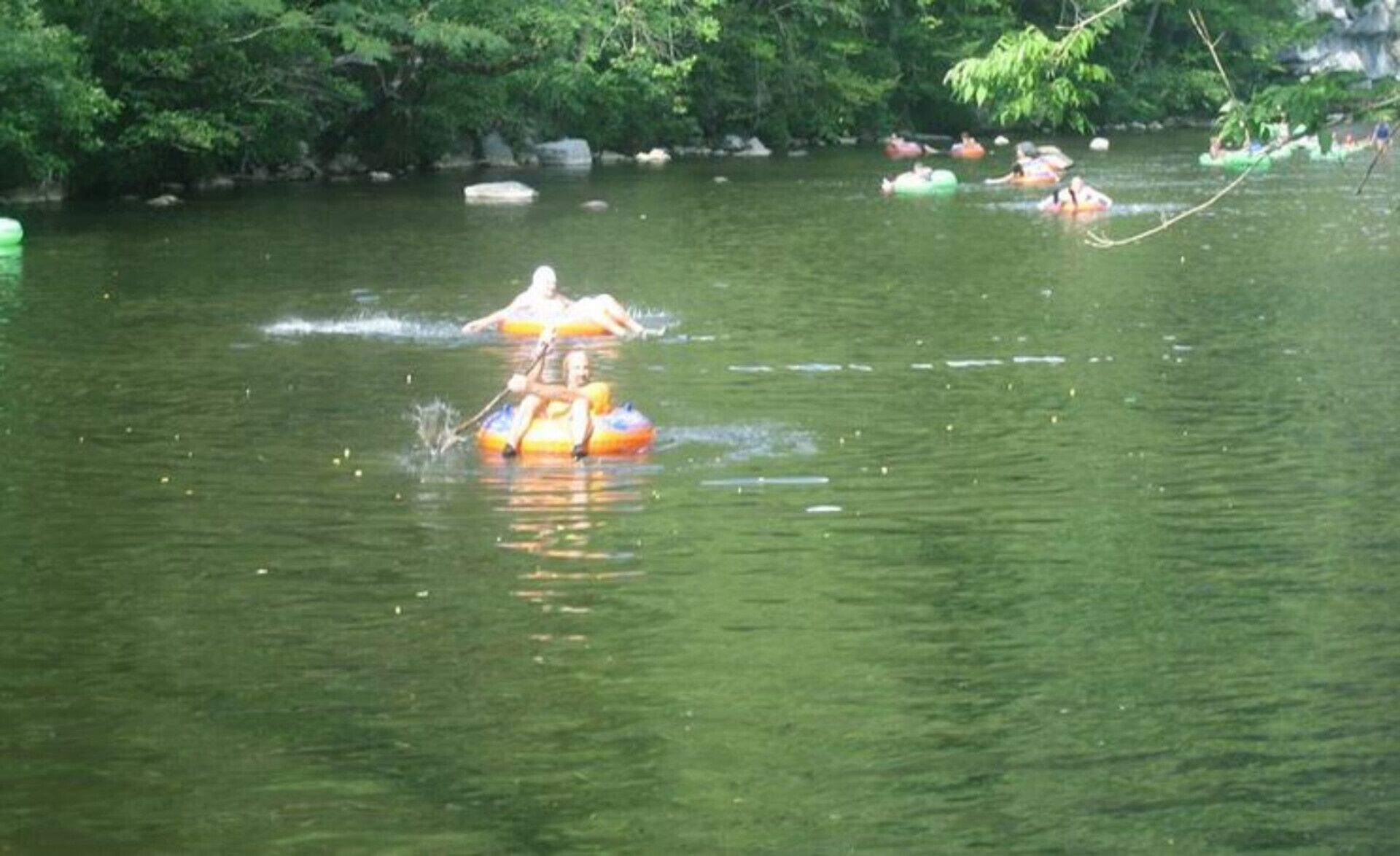 A body of water with several people floating on inflatable tubes.