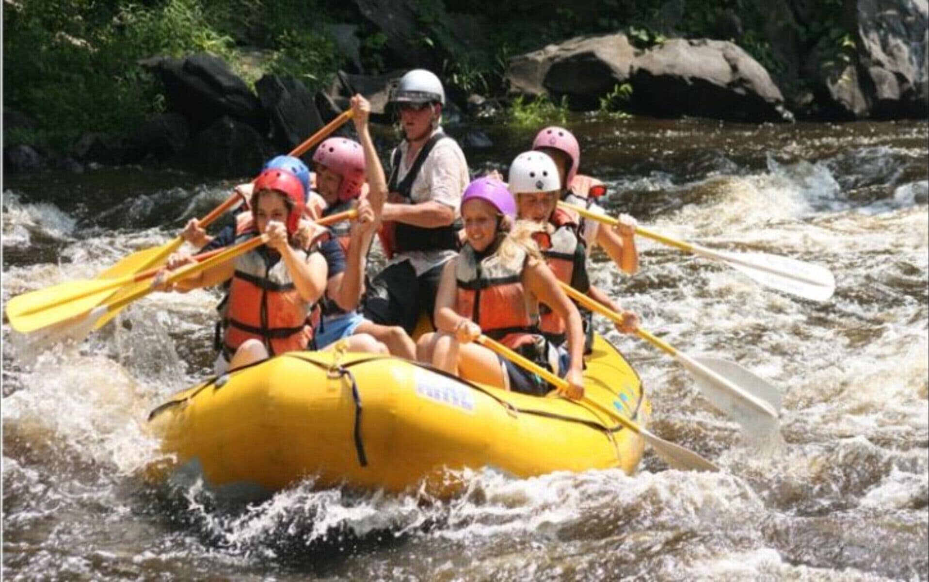 Un grupo de personas en un bote amarillo navegando por un río.