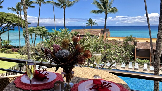 A dining area with a view of the ocean, palm trees, and a pool. - Amazing panoramic ocean view!   Perfect for couples. Just steps to the ocean.🏝 (Lahaina)