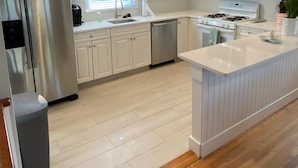 Une cuisine moderne avec des meubles blancs, des appareils en acier inoxydable et un plancher en bois.