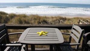 Mesa y sillas con vista a una playa y olas.