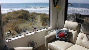 Una habitación con un amplio ventanal con vistas al océano, un sofá de cuero color beige y una pequeña mesa con objetos decorativos.