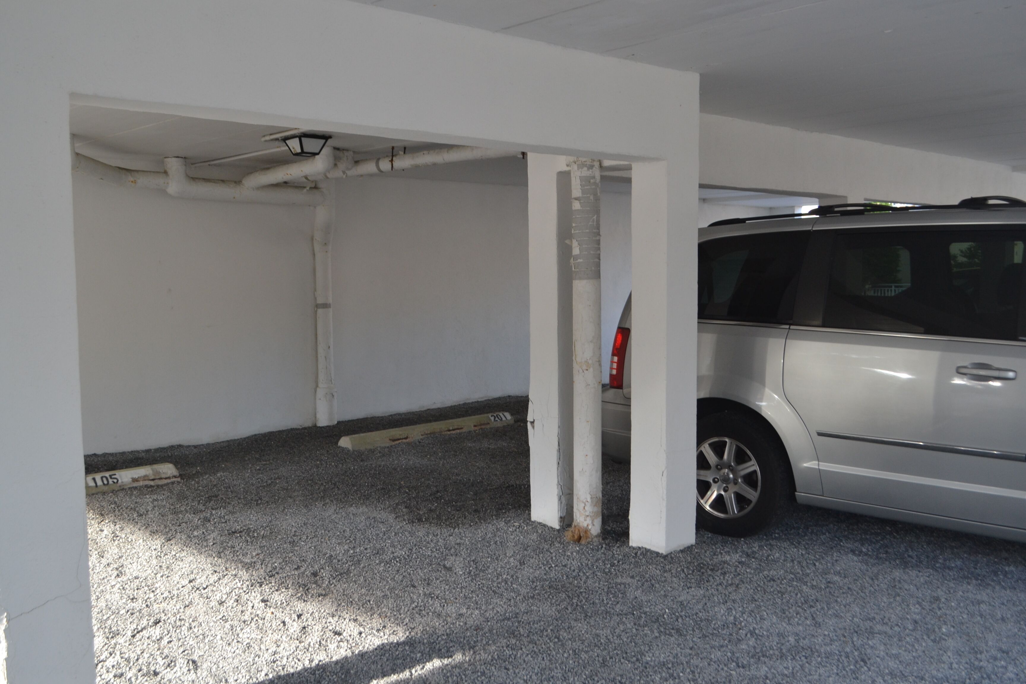 A parking garage with a white van parked in a spot.