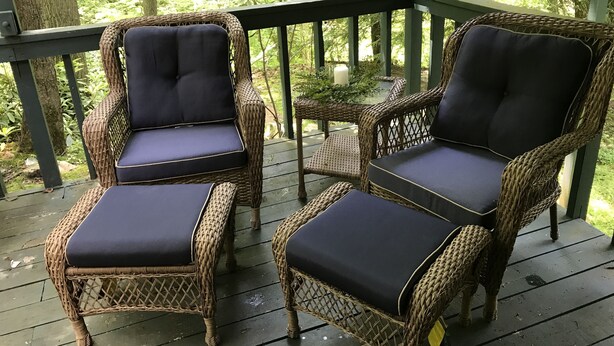 A wooden deck with wicker chairs and a table.