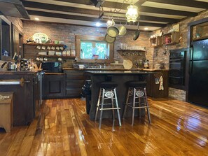 Una cocina con una isla de madera, taburetes de bar, un refrigerador y una ventana con vistas.