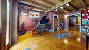Une pièce spacieuse avec un magnifique piano à queue, un parquet en bois et une cheminée chaleureuse.