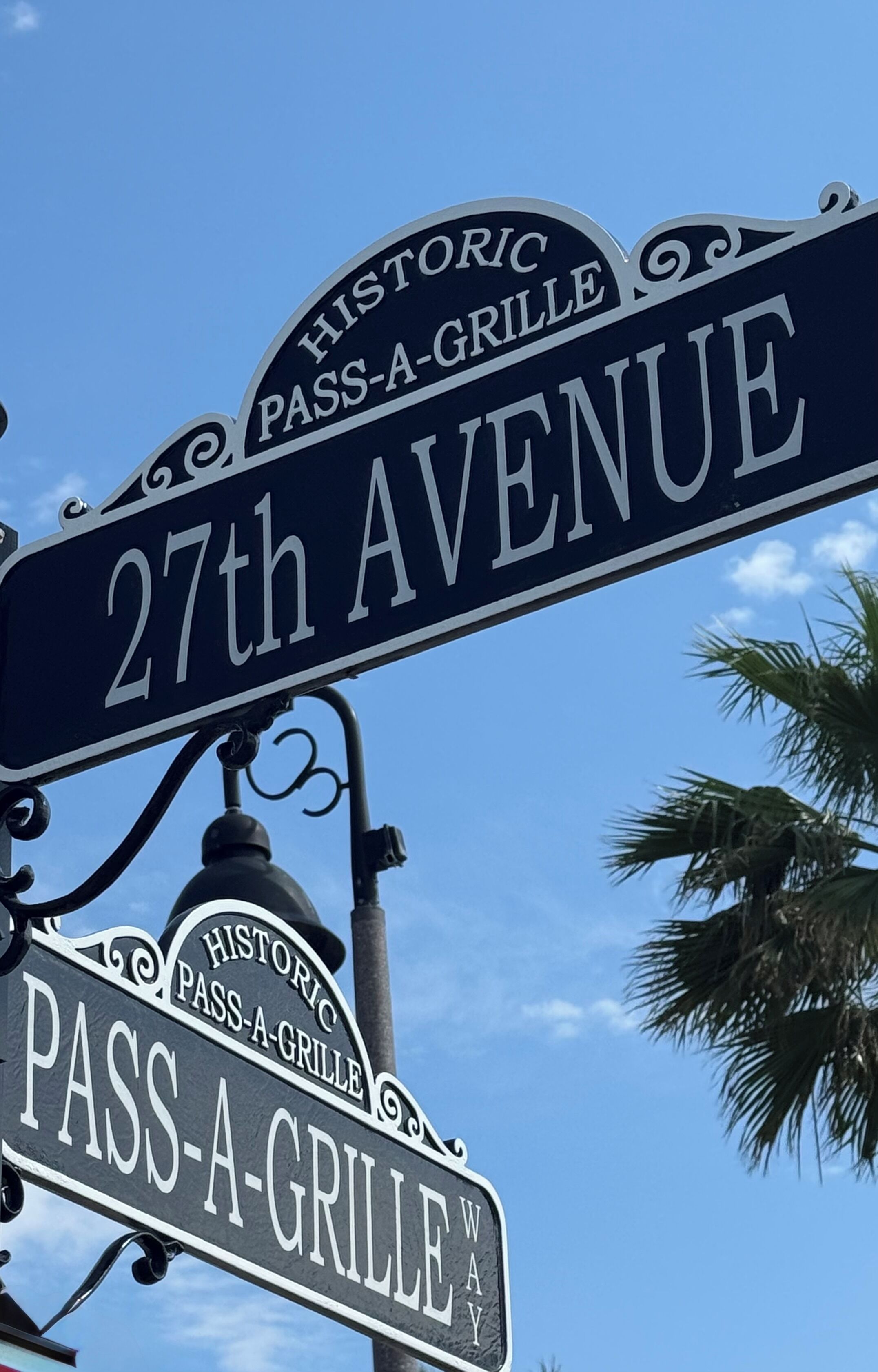 A street sign for '27th Avenue' and 'Pass-A-Grille Way' with a decorative lamp post.