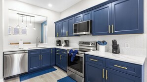 A modern kitchen with dark blue cabinets, stainless steel appliances, and a white countertop. - Welcome to The Windsor Magic with Professional Arcade Room! Brand New 2024! (Kissimmee)