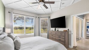 A bedroom with a bed, a TV, a ceiling fan, and large windows. - Welcome to The Windsor Magic with Professional Arcade Room! Brand New 2024! (Kissimmee)