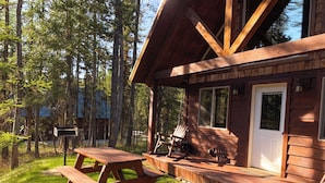 A wooden cabin with a porch, picnic table, and rocking chair.