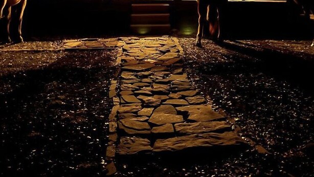 Una cabaña de madera con porche, un camino de piedra y caballos.