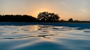 Una masa de agua tranquila con formaciones de hielo y la silueta de un árbol contra un cielo al atardecer.