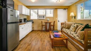 A compact kitchen with white cabinets, a stainless steel refrigerator, and a dining area with a wooden table and chairs. - Surfer's Dream Condo w/ Full Kitchen - Free Wifi, Sleeps 4 (Honolulu)