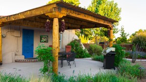 A patio with a pergola, a blue door, and a barbecue grill.