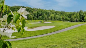 Un parcours de golf avec une pelouse bien entretenue, des bunkers de sable et un ciel dégagé.