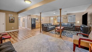 Un salon spacieux avec un grand tapis, une cheminée et un téléviseur.