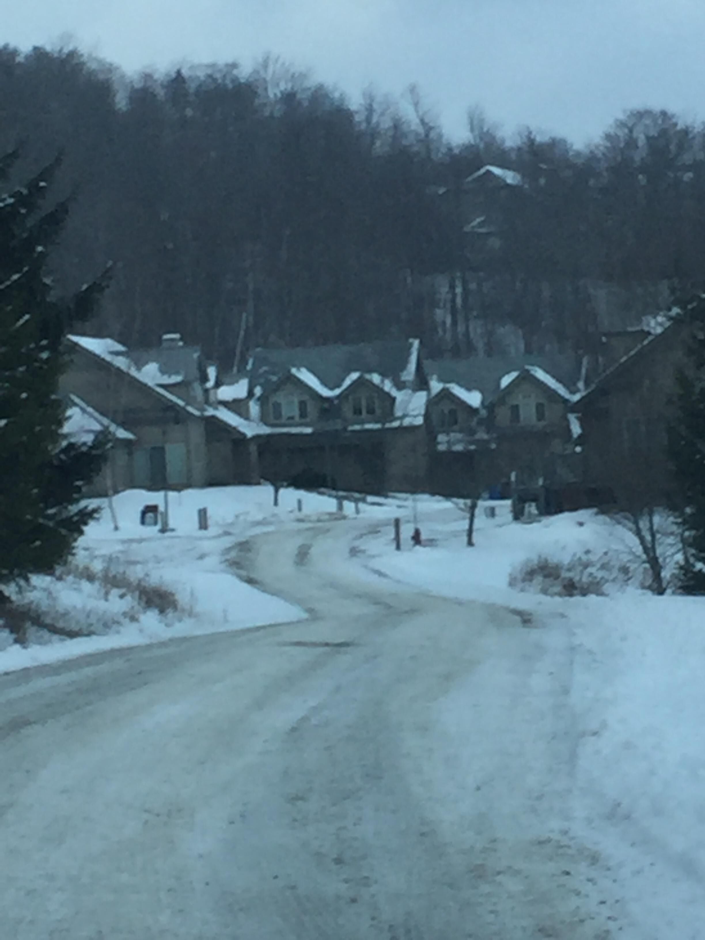 Uma estrada coberta de neve que leva a um conjunto de casas com telhados inclinados.