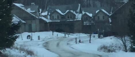 Uma estrada coberta de neve que leva a um conjunto de casas com telhados inclinados.