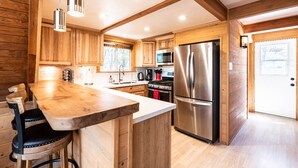 A modern kitchen with wooden cabinetry, stainless steel appliances, and a central island. - Mountain A-Frame, Wall of Glass w/Stunning Tree Views, Hot Tub, Firepit, Dogs ok (Lake Arrowhead)