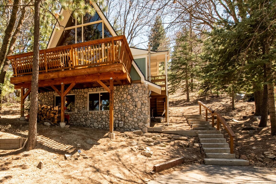 Eine Holzhütte mit Steinaußenwand, einer Holzdiele und einer Treppe zu einer Holzterrasse.