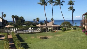 A resort with a well-maintained lawn, palm trees, and a view of the ocean. - Kihei Ground-Floor Condo • Steps to Kamaole III Beach• King Bed • Pool & A/C (Kihei)