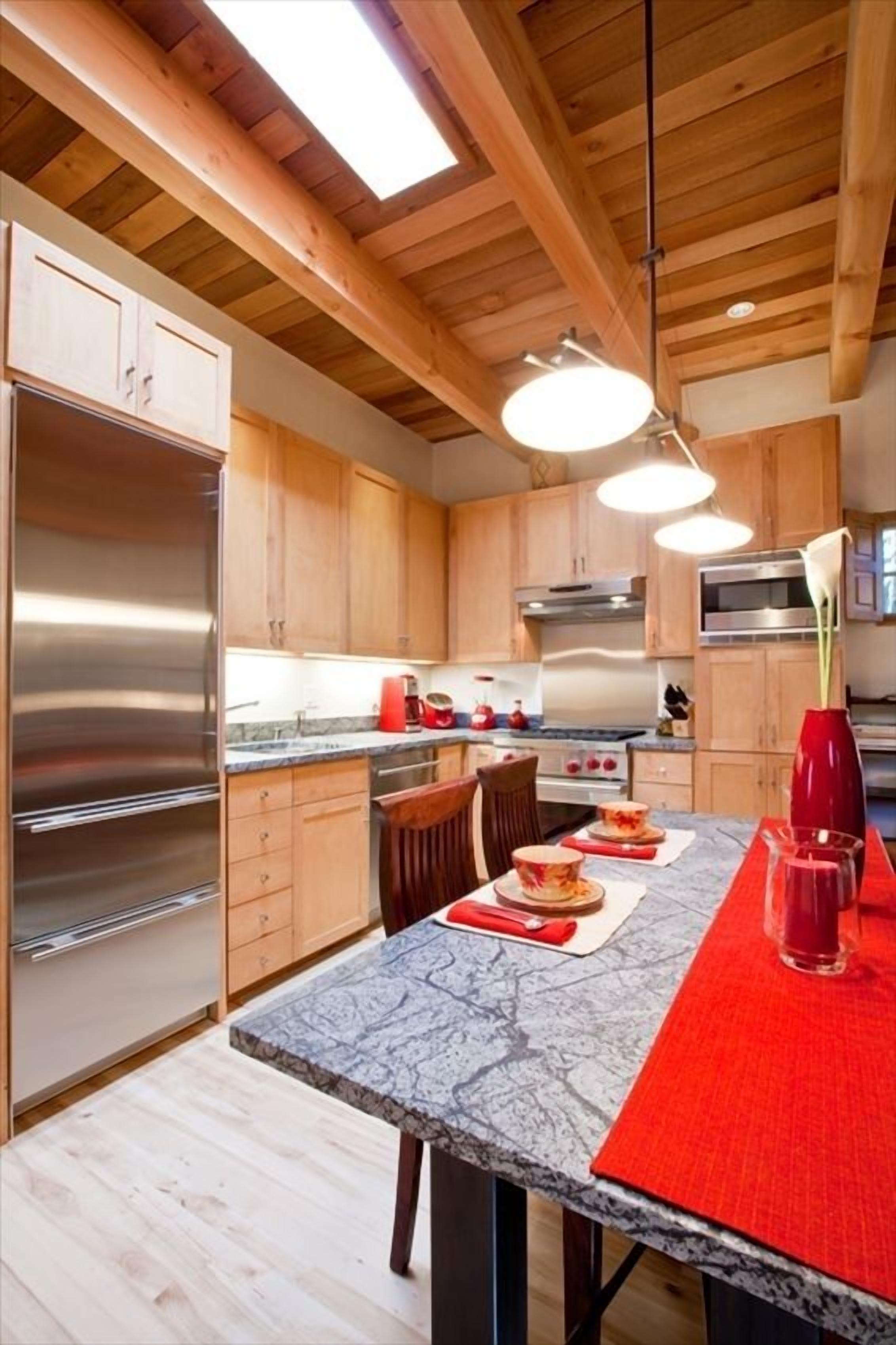 A modern kitchen with wooden cabinets, stainless steel appliances, and a marble countertop.
