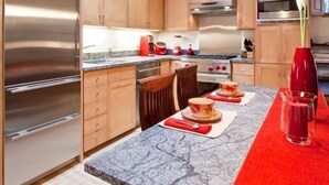 A modern kitchen with wooden cabinets, stainless steel appliances, and a marble countertop.