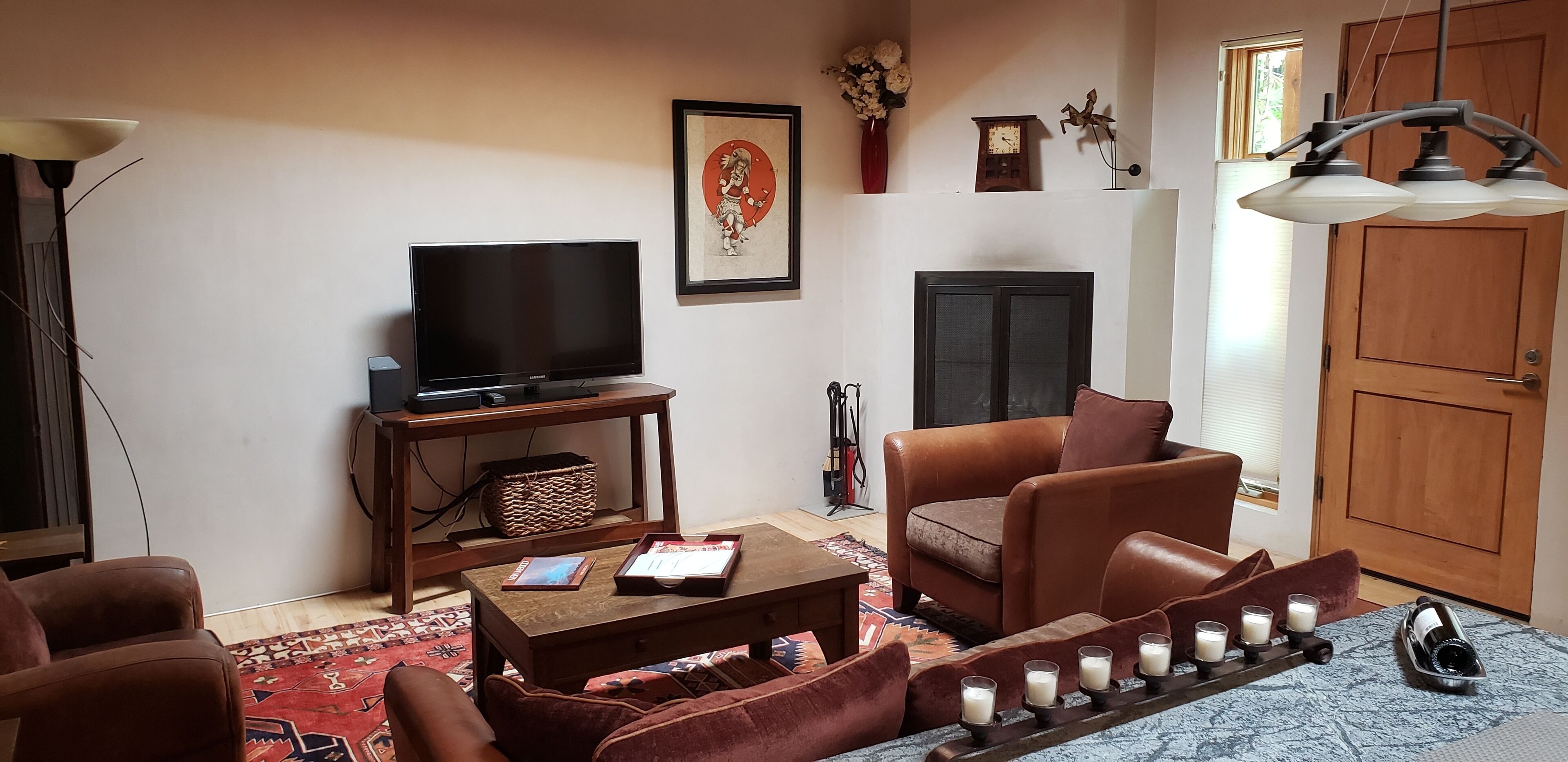 A living room with a television, leather sofa, coffee table, and a decorative candle arrangement.