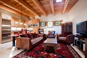 A modern living room with a wooden ceiling, a sofa, a coffee table, and a television.