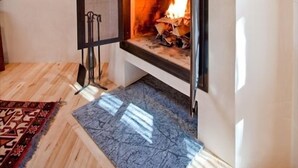 A fireplace with a clock above it, a framed picture on the wall, and a patterned rug on the floor.