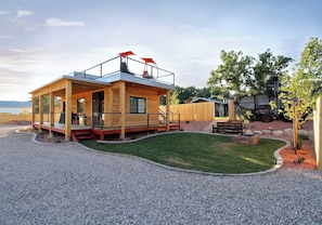 A wooden cabin with a balcony, a gravel driveway, and a lawn. - Tiny Home near Zion with Rooftop Stargazing Deck (Orderville)