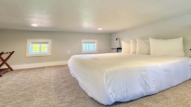A bedroom with a large bed, two windows, a ceiling fan, and a wooden chair. - Tiny Home near Zion with Rooftop Stargazing Deck (Orderville)