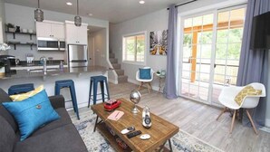 A modern living space with a kitchen, dining area, and a large sliding glass door to a patio. - Tiny Home near Zion with Rooftop Stargazing Deck (Orderville)