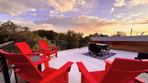 A rooftop patio with red Adirondack chairs, a table, and a view of the sunset. - Tiny Home near Zion with Rooftop Stargazing Deck (Orderville)