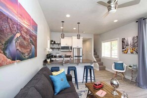 A modern living room with a sofa, a coffee table, and a dining area with bar stools. - Tiny Home near Zion with Rooftop Stargazing Deck (Orderville)